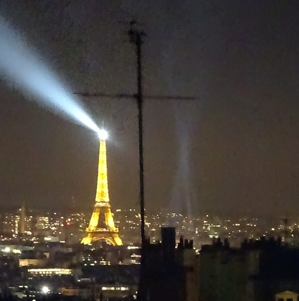 The Eiffel Tower at night, with a cross in the air, shadowing it