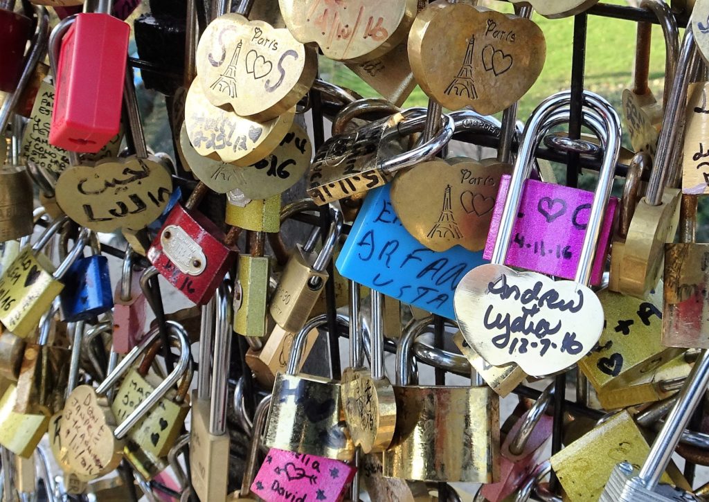 dozens of padlocks with inscriptions, locked to a fence