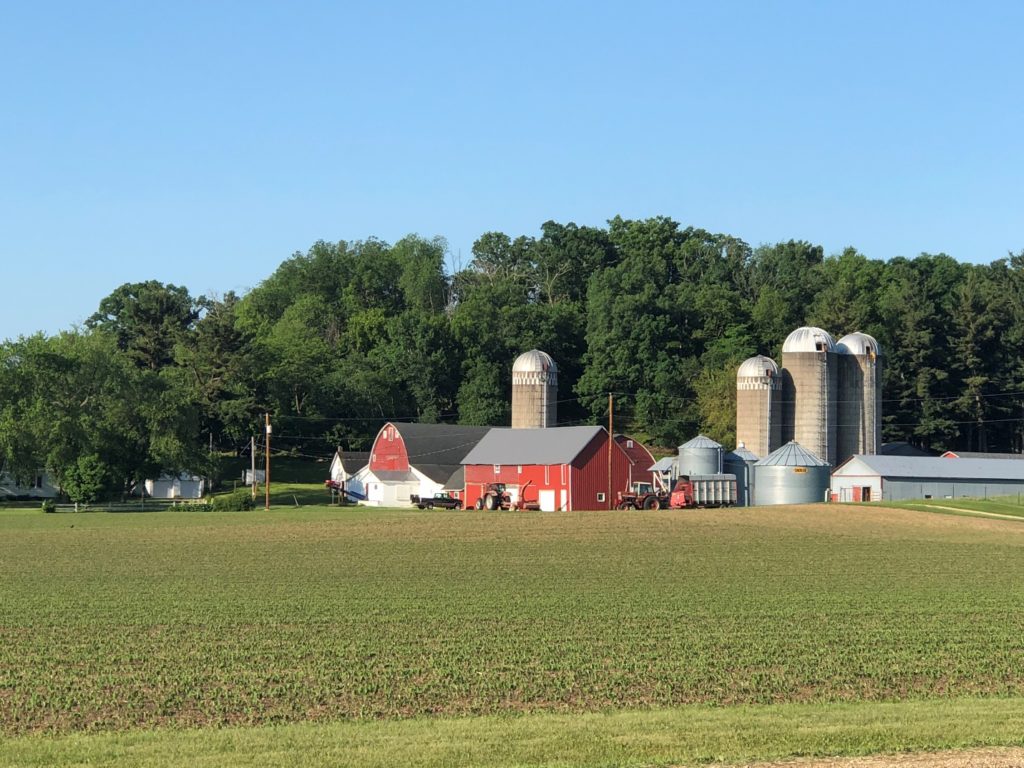 Red barn and silo behind farm field